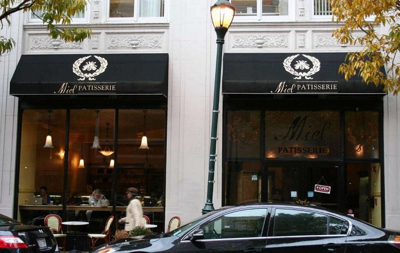 The former Miel Patisserie at 204 S 17th St, with black Miel awnings, a street lamp out front and cafe seating along the sidewalk